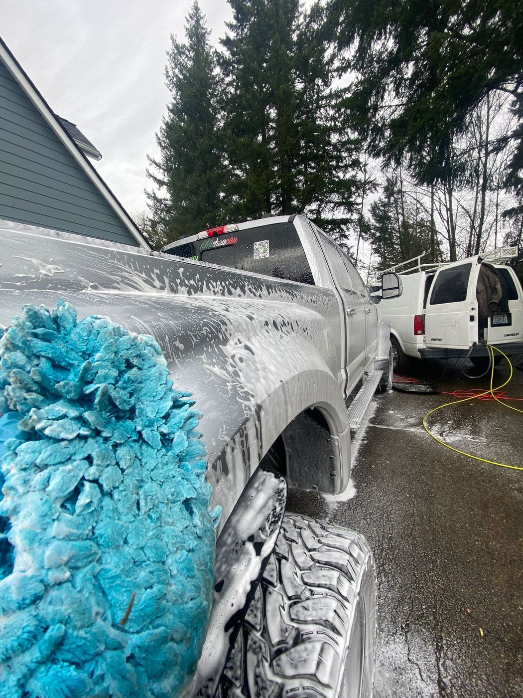 Hand washing a foamed pickup with a blue microfiber mitt